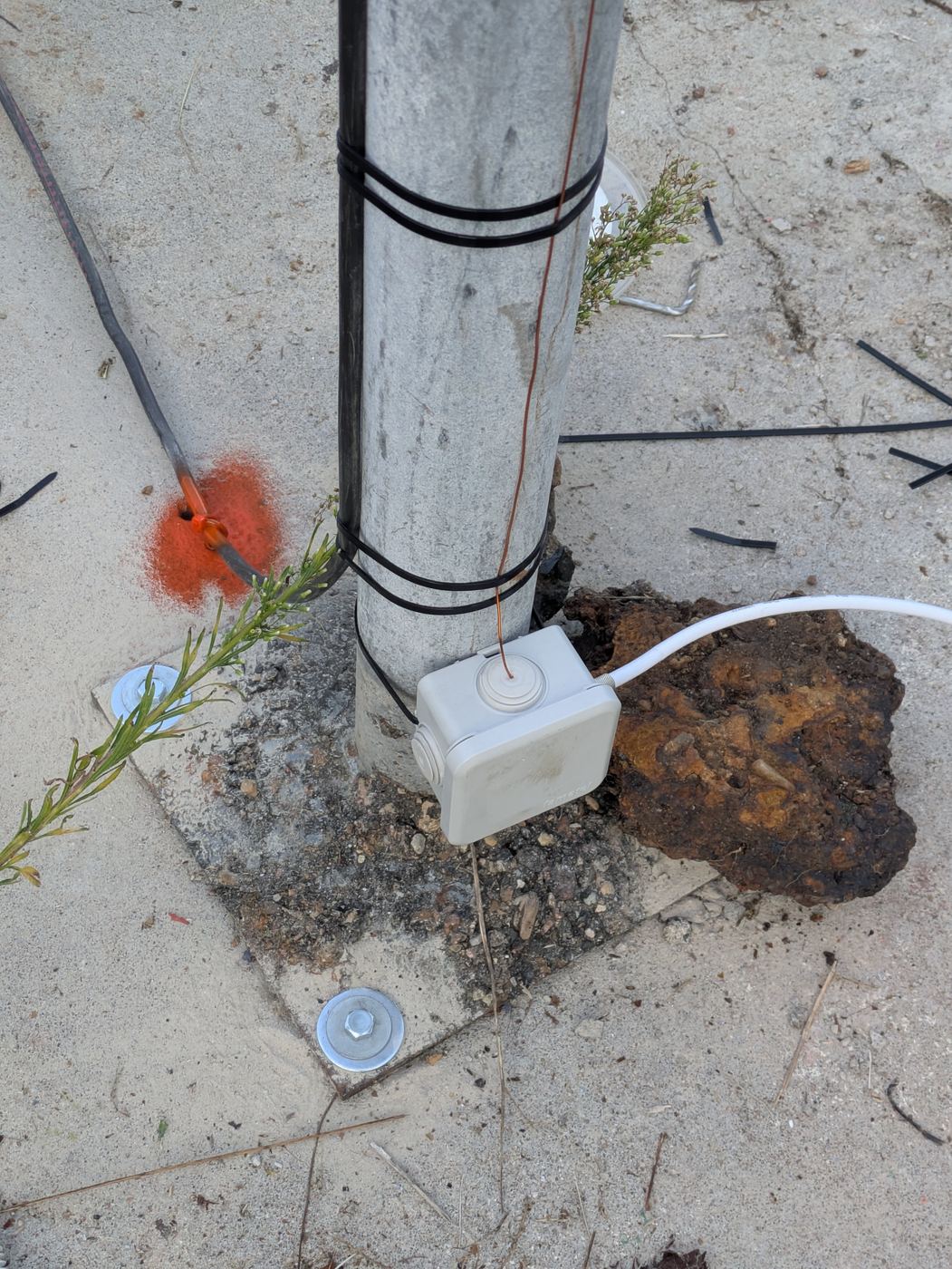 Base of the NEUTRAL HOST mast: junction box and copper down-lead running into the ground